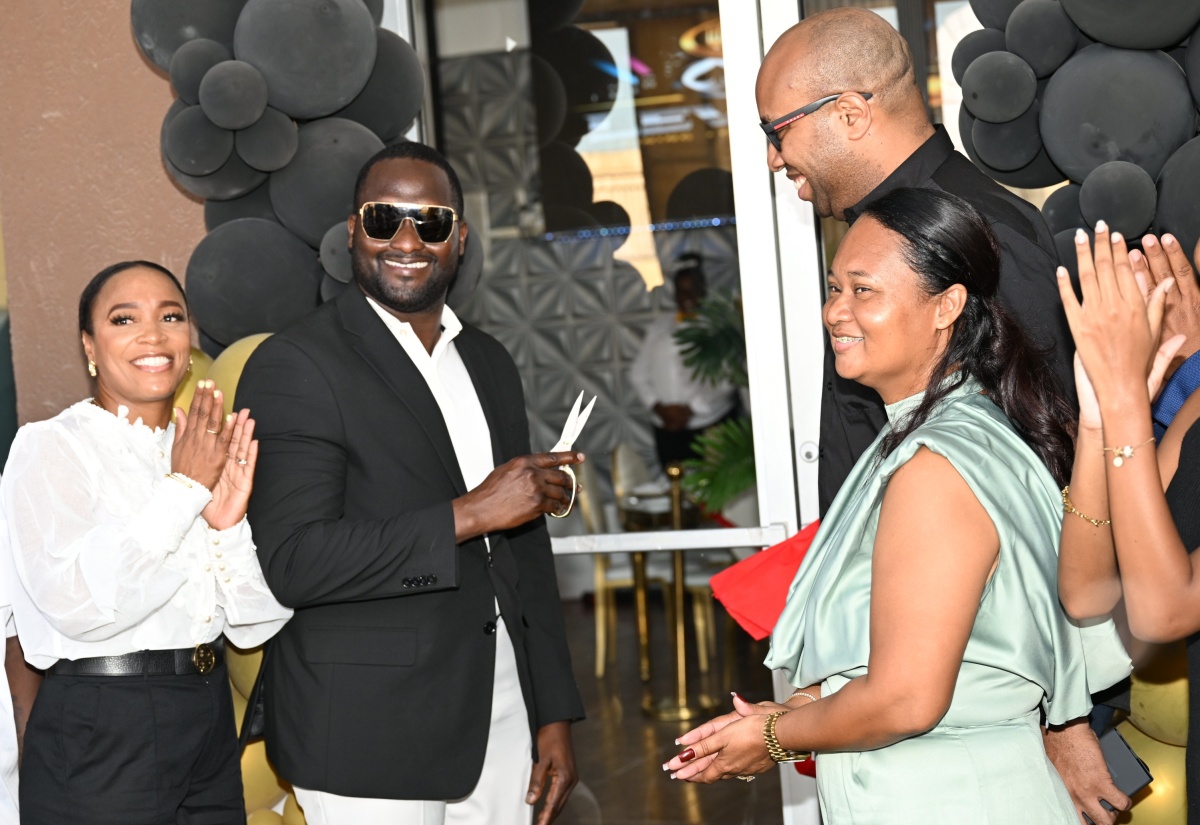 Minister of State in the Ministry of Industry, Investment and Commerce, Hon. Delano Seiveright (second right), looks on as Chief Executive Officer of Level 8 – Bakery, Dining and Gaming Lounge, Richard Cole, cuts the ribbon to mark the grand opening of the new establishment in Black River, St. Elizabeth, on Saturday (February 28). Sharing the moment are President of the St. Elizabeth Chamber of Commerce (Black River Chapter), Kadian Myers-Brown (left), and Level 8 co-owner, Taquilia Chin-Cole.