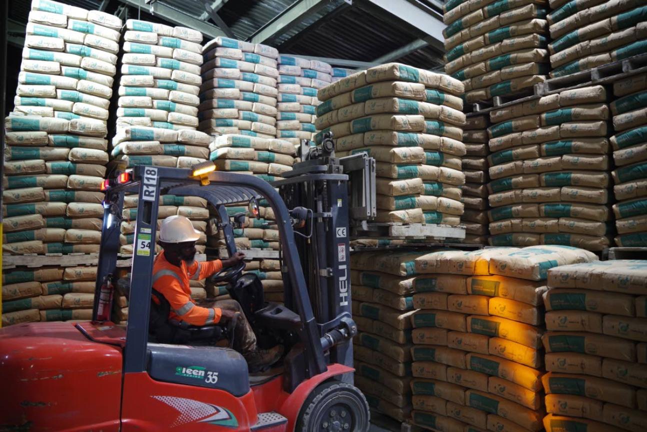A worker in a building picking up cement with a forklift.