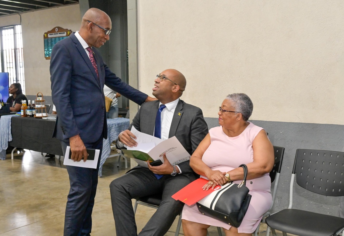 State Minister in the Ministry of Industry, Investment and Commerce, Hon. Delano Seiveright (seated centre), converses with President of the East Jamaica Conference (EJC) of Seventh-day Adventists, Dr. Meric Walker (standing left), during the church's Expo on Sunday (May 3) at the Jamaica College Auditorium in St. Andrew, under the theme 'Empowering Families and the Generations Following'. Retired Managing Director of the Jamaica Stock Exchange, Dr. Marlene Street Forrest, shares in the conversation.